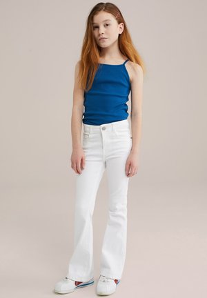 Blå ärmlös topp, vita utsvängda jeans, vita sneakers med röda och blå accenter. Slät tyg, enkel design och minimalt med detaljer.