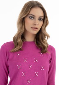 Pulover fuchsia cu embellishments de perlă rotundă în model de stea. Design clasic cu guler rotund și textură moale de tricot, siluetă ajustată.