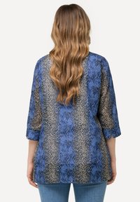 Blusa blu con motivo a stampa che presenta maniche a tre quarti, una vestibilità ampia e una stampa simile a quella di una leopardata in tonalità beige e blu scuro.