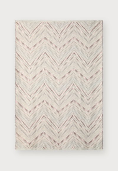 Pătură cu model geometric, având un fundal crem și dungi în zigzag de culoare roșie și albastră. Textură moale și formă rectangulară.
