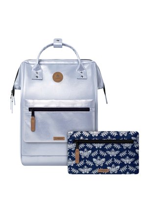 Silberner rechteckiger Rucksack mit Frontreißverschlusstasche und oberen Griffen, gezeigt mit einem marineblauen Reißverschluss-Etui mit weißem Schmetterlings- und Blattmuster.