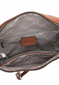 Binnenkant van een bruine leren tas met een grijs patroon, voorzien van een ritsvak en een klein leren label. Duurzame ritsrand.