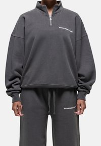 Pullover grigio con colletto a mezza zip, vestibilità ampia e logo in bianco. Materiale misto cotone, polsini e cintura a costine.