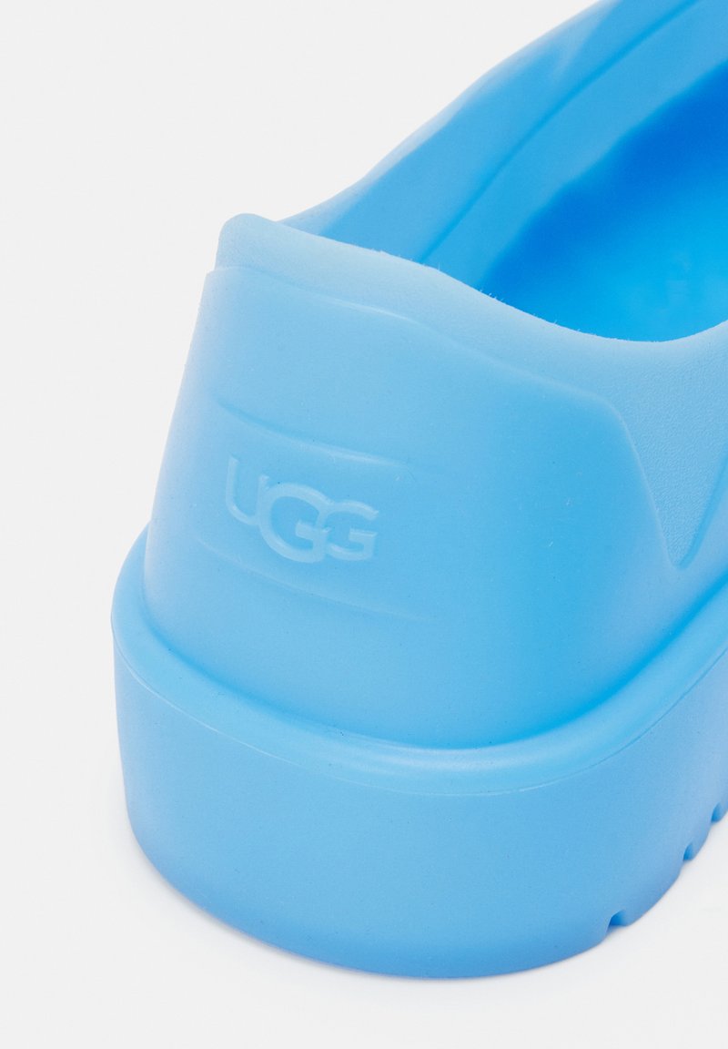 Niebieski but wsuwany z żywicy z teksturowaną cholewką i formowanym obcasem. Posiada wytłoczone logo oraz okrągłą podeszwę dla wygody.