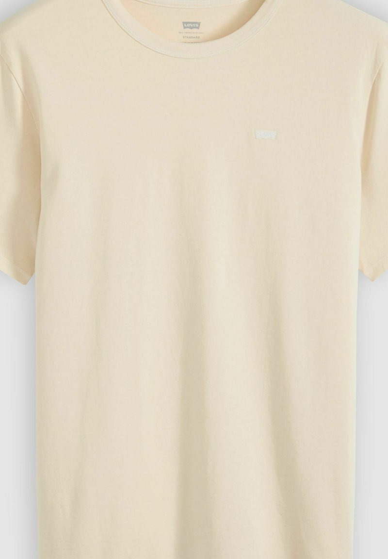 T-shirt beige a maniche corte con scollo rotondo, con una piccola toppa del logo Levi's sul petto sinistro, mostrata su sfondo semplice.