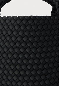 Μαύρη υφασμάτινη τσάντα ώμου με υφή, που διαθέτει πλεκτό σχέδιο και ανθεκτικές λαβές. Το υλικό φαίνεται απαλό αλλά ανθεκτικό.