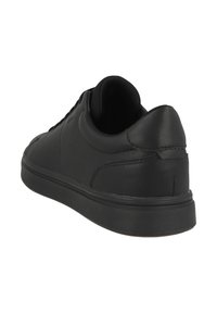 Zapatilla negra de cuero con una textura suave, perfil bajo, punta redondeada y suela de goma negra a juego. Presenta detalles de costura sutiles.