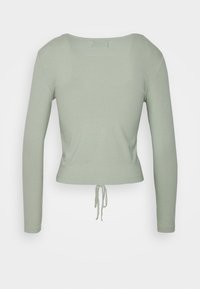 Svetle zelený, žebrovaný crop top s dlouhým rukávem, kulatým výstřihem a nastavitelností na spodním okraji. Hladká textura, přiléhavý střih.