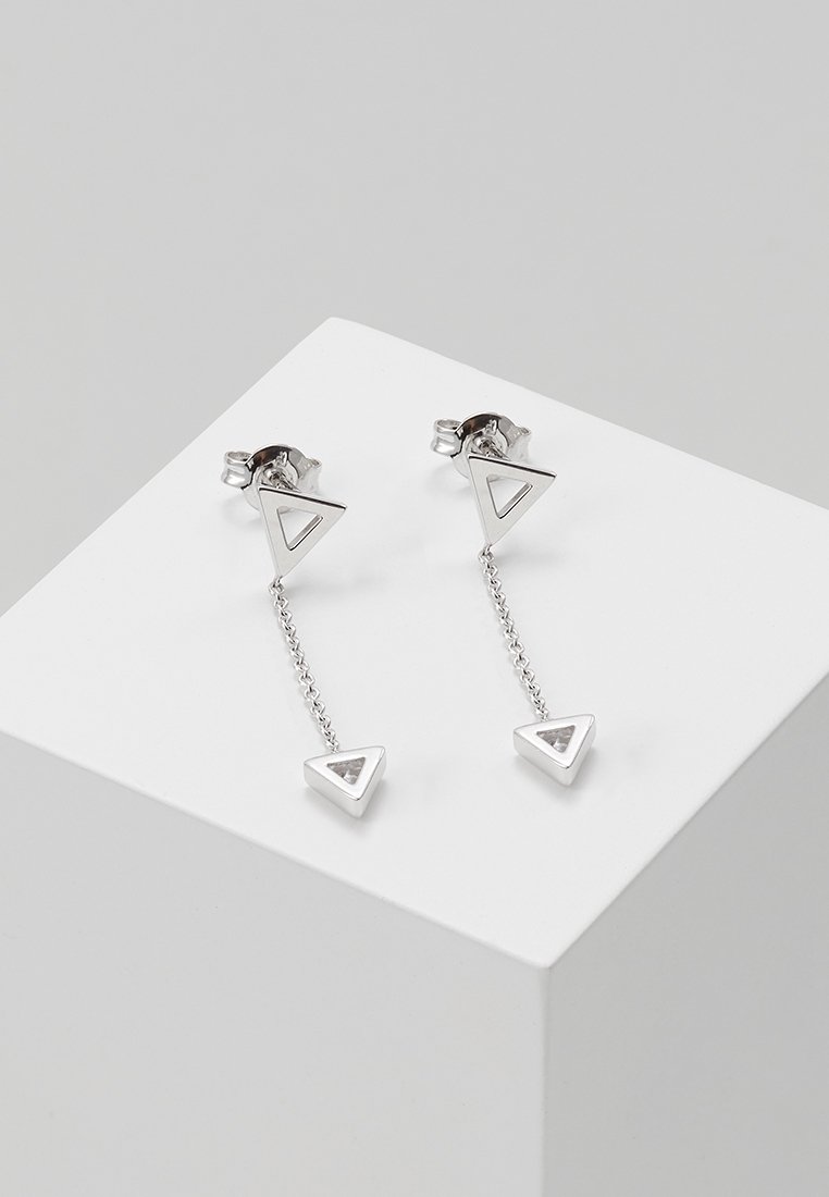 Boucles d'oreilles pendantes géométriques en argent avec des clous triangulaires ouverts reliés par de fines chaînes à des pendentifs triangulaires pleins.