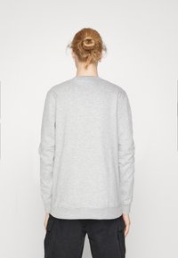 Harmaa collegepaita, jossa on pitkät hihat, pyöreä kaula-aukko, resorit hihansuissa ja helmassa. Sileä pinta, yksinkertainen muotoilu ilman näkyviä kuvioita tai korostuksia.