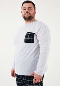 Hallikas pikasleeve särk musta ruudulise taskuga. Pehme tekstuur, ringkrae disain ja laiem sobivus. Kombineeritud ruuduliste pükstega.