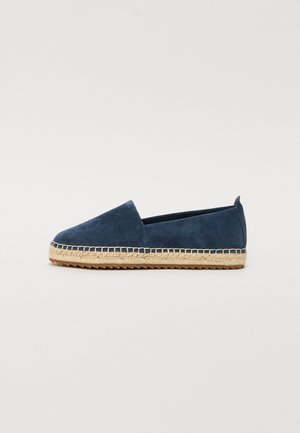 Suede navy slip-on shoes with a braided jute sole, featuring a rounded toe and minimalistic design. Soft texture and clean lines.