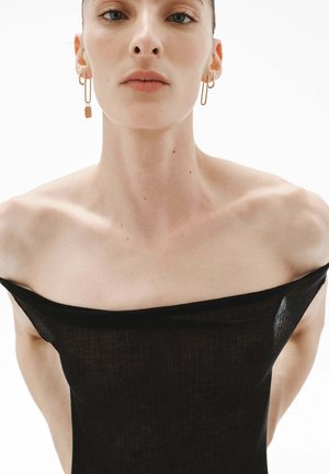 Vestido negro sin mangas con un diseño ajustado, que cuenta con un material ligero y texturizado. Pendientes de aro dorados añaden contraste.