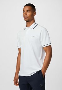 Biele polo tričko s námorníckym prúžkovaným golierom a akcentmi na rukávoch, s malým logom "HACKETT" na hrudi. Mäkkučký, ľahký materiál.