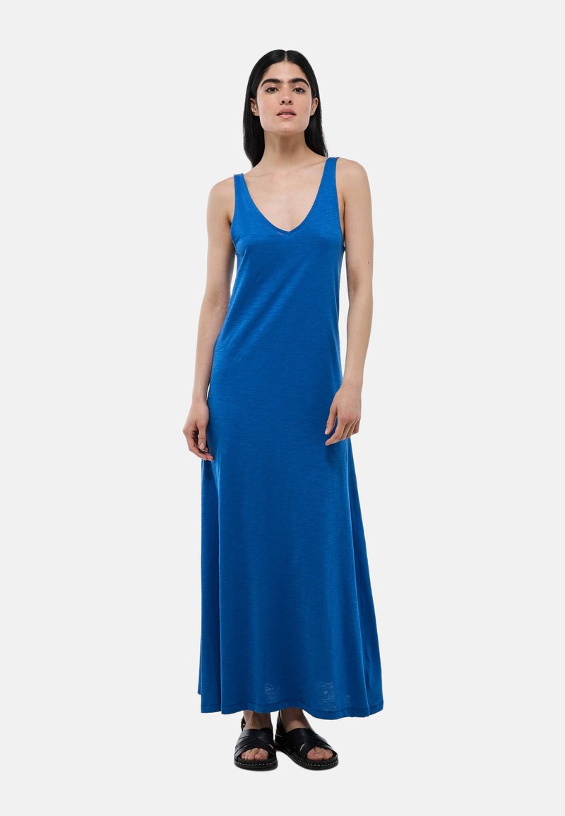Robe maxi sans manches bleue avec décolleté en V, fabriquée à partir d'un tissu lisse. Présente une coupe décontractée et arrive aux chevilles. Associée à des sandales noires.