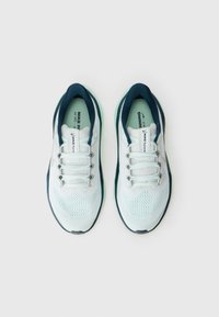 Une paire de chaussures de course Nike blanches et navy avec une tige en maille et des lacets, vue de dessus sur un fond clair.