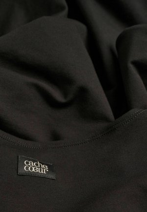 Tissu noir extensible avec une texture lisse, présentant un bord cousu et une étiquette indiquant "cache cœur". Apparence douce et drapée.