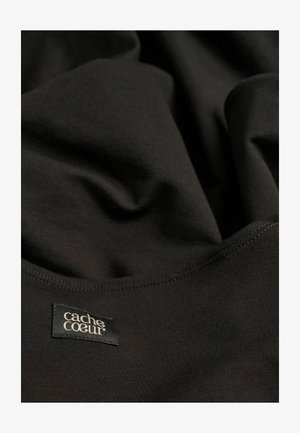 Schwarzer, dehnbarer Stoff mit glatter Textur, einer genähten Kante und einem Etikett mit der Aufschrift "cache cœur". Weiche drapierte Optik.