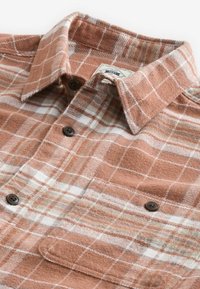 Brown and white plaid flannel shirt featuring a collar, button closure, and chest pocket with a single button. Soft textured fabric.