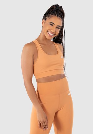 Sports-bh og leggings sæt i lys orange, lavet af strækbart materiale; har en scoop halsudskæring og elastisk bælt, med minimale branddetaljer.