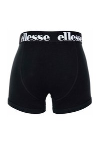 Musta puuvillapöksyt, joissa on leveä valkoinen jousto-osa, jossa on "ellesse"-logo, minimalistinen muotoilu ja sileä pinta.