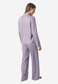 Ensemble de pyjama rayé dans des tons de violet clair et de rose, comprenant une chemise à manches longues avec col et un pantalon assorti à la coupe décontractée.