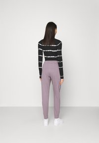 Top a maniche lunghe a righe bianche e nere abbinato a pantaloni jogger color lavanda; i pantaloni presentano una vita con coulisse e polsini elasticizzati, con tasche nascoste.