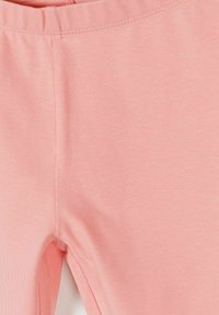 Leggings en tissu extensible rose doux avec une taille élastique et une vue en gros plan de l'entrejambe et de la partie supérieure de la cuisse.