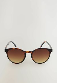 Occhiali da sole tartarugati con lenti rotonde, gradiente marrone e una montatura spessa. Gli accenti metallici sulle tempie arricchiscono il design.