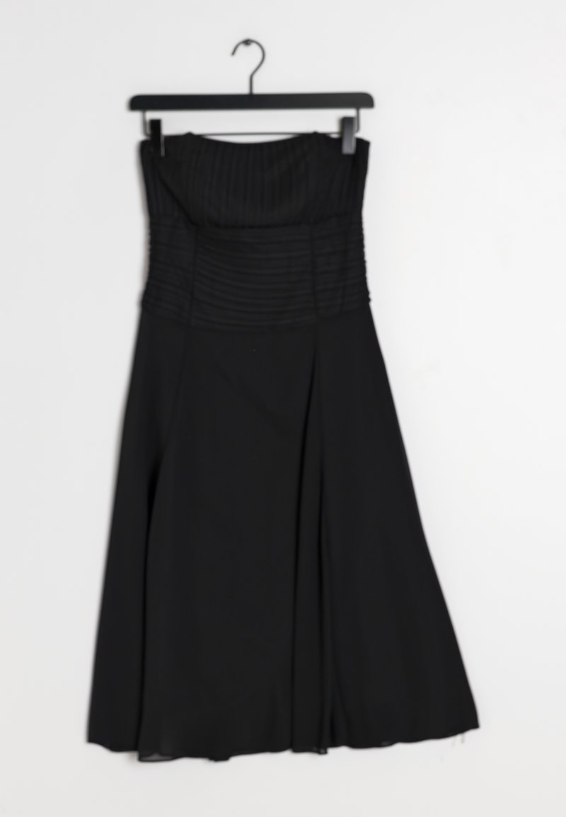 Černé šaty bez ramínek s vertikálními sklady na předním díle, splývavou sukní a hladkou texturou. Visí na černém plastovém ramínku.