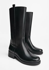 Zwarte leren kniehoge boots met een gladde afwerking, blokhakken en gebogen bovenkanten. Bevat stitchingsdetails langs de zijkanten.
