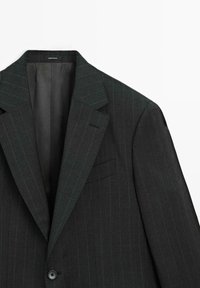 Dunkelgrauer Blazer mit Nadelstreifen, mit Reverskragen, einem Knopf zum Schließen und einer Brusttasche. Glattes Innenfutter, taillierte Passform.