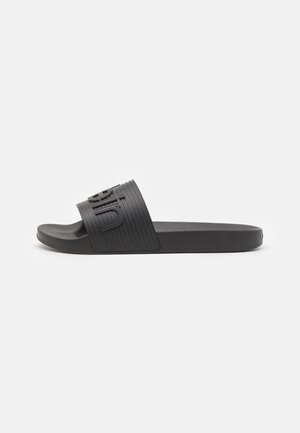 Black slide sandal with a textured rubber strap, featuring a raised logo. The sole is flat and made of durable material.
