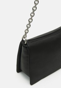 Borsa a mano in pelle nera con forma rettangolare, caratterizzata da una superficie texturizzata e una tracolla in catena metallica. Chiusura con cerniera visibile.