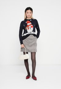 Navy sweater with snowman design, red scarf, and white snowflakes. Houndstooth skirt, black tights, red flats, and a small white handbag.