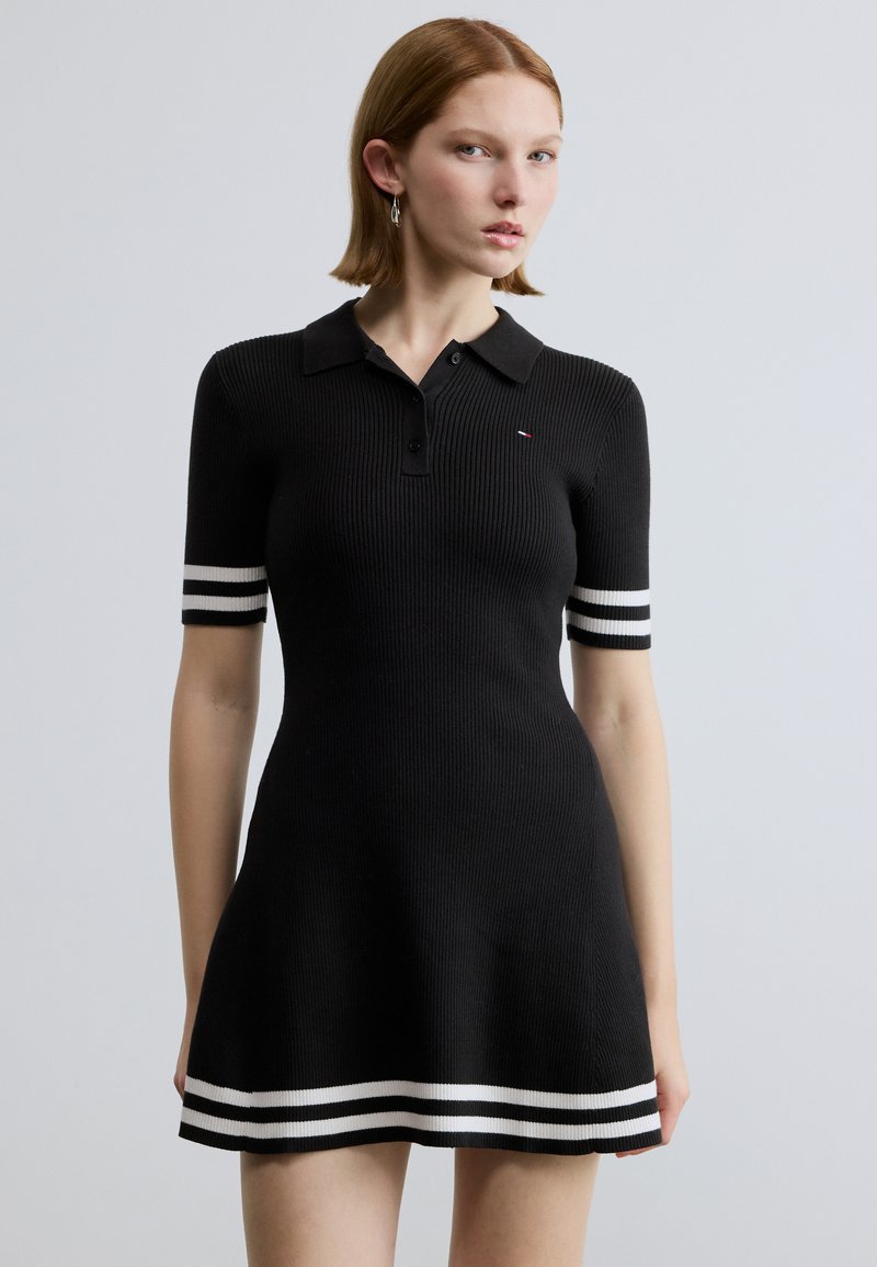 Melna ribota polo kleita ar īsām piedurknēm, ar baltām svītrainām aprocēm un apakšmala. Apkakles aiztaisīšana ar pogām un neliels logo uz krūtīm.