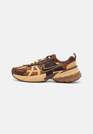 Brązowo-beżowy sneaker Nike z siateczkowymi i skórzanymi detalami, grubą podeszwą, pętelką na pięcie oraz wyraźnym logo Nike swoosh po boku.