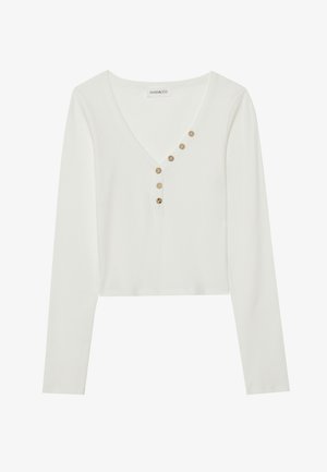 Witte, lange mouwen, ribbed top met een V-hals en zes decoratieve bruine knopen langs de knoopsluiting. Casual cropped ontwerp.