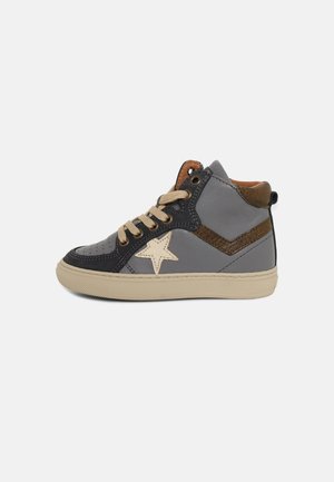 Zapatilla alta gris y negra con cordones beige, decoración de estrella en el lado, acentos marrones y suela beige sobre fondo blanco.
