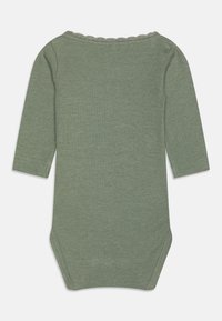 Ribbet grønn bodysuit med lange ermer, med en scalloped halslinje og trykknapper nederst. Myk tekstur og elastisk passform.