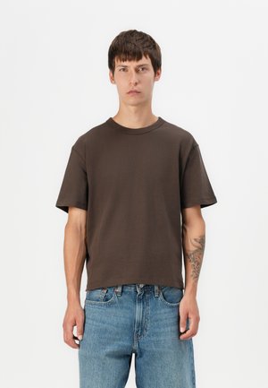 Brown short-sleeve t-shirt, crew neck, relaxed fit, cotton material, smooth texture, worn with light blue denim jeans.