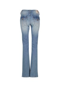 Šviesiai mėlynos džinsinės kelnės su platėjančiomis kojomis, siuvinėti užpakaliniai kišeniai su mygtukais, ir maža rusva prekės ženklo etiketė ant juosmens.