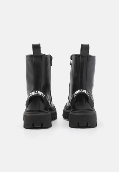 Črne usnjene gležnjarje s debelim podplatom, zadnjim zadrgo in trakcem za vlečenje. Imajo bel logotip na peti in teksturiran podplat.