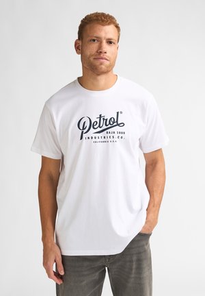 Tricou alb din bumbac cu un logo negru imprimat care spune "Petrol BAJA 1000 INDUSTRIES.CO. CALIFORNIA U.S.A." Mâneci scurte, guler rotund.