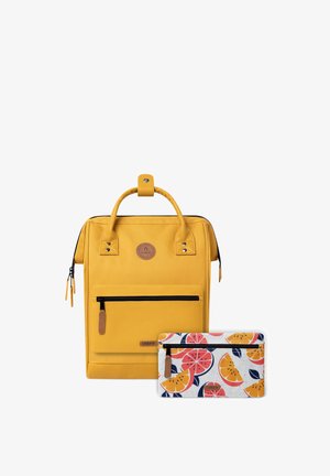 Sac à dos en tissu jaune avec des poignées supérieures, une poche zippée avant et des accents en cuir ; comprend une petite pochette avec un motif de fruits.