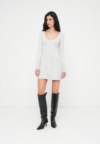 Γκρι ριμπ πλεκτό φόρεμα με μακριά μανίκια και λαιμόκοψη scoop, συνδυασμένο με μαύρες μπότες μέχρι το γόνατο με μυτερή μύτη και τακούνι στιλέτο.