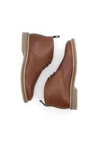 Bottines en cuir marron avec bout arrondi, laçage sur le côté et semelle beige texturée. Pas de motifs ou de détails en matériel notables.