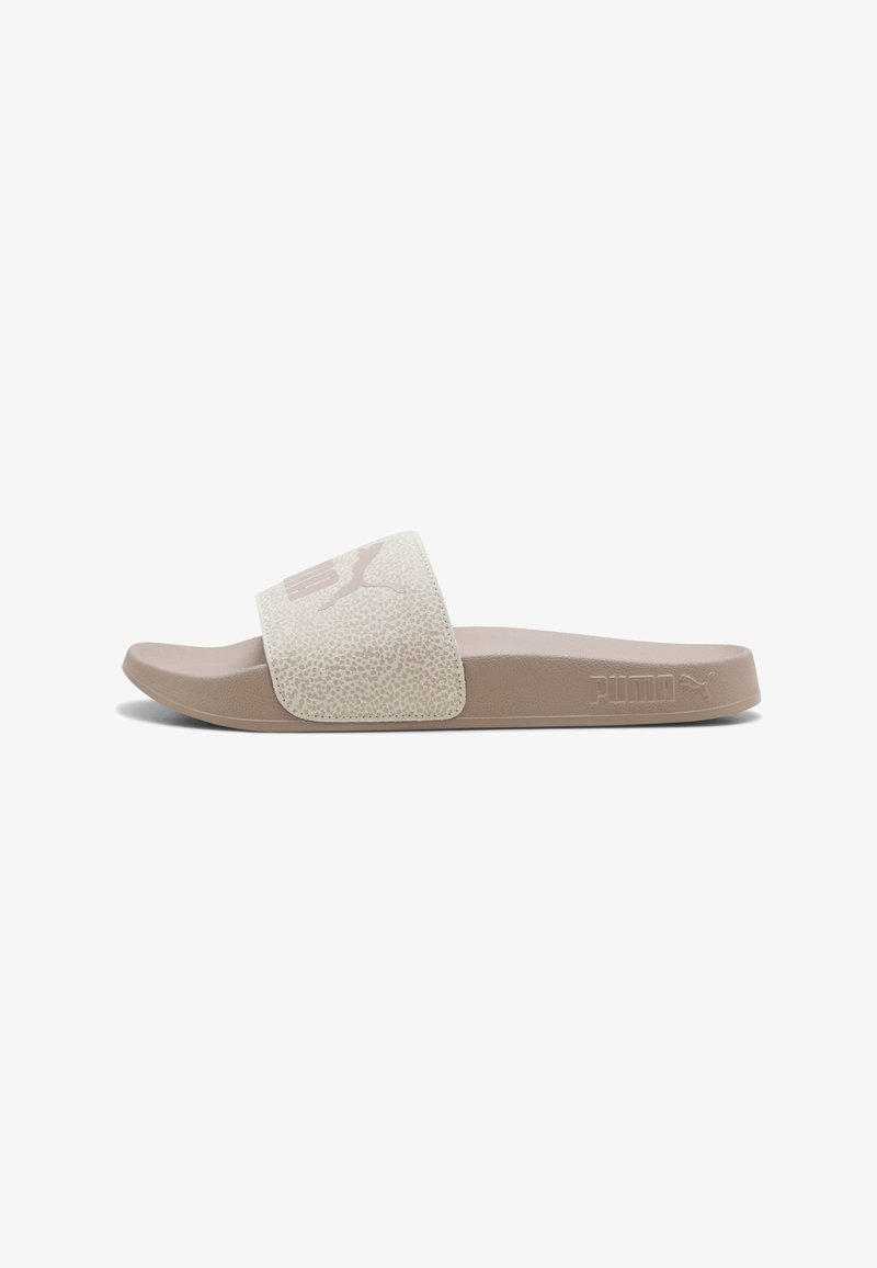 Sandale slide beige Puma avec une large bride texturée et un logo Puma embossé sur le côté de la semelle, vue de côté.