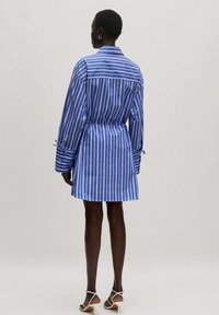 Gestreiftes Hemdkleid in Blau und Weiß mit langen Ärmeln, tailliertem Schnitt und Knopfmanschetten. Glattes Material mit maßgeschneidertem Schnitt.