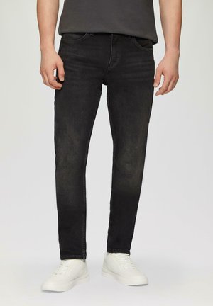 Zwarte denim jeans met een slim fit, vijf-pocket ontwerp en subtiele vervaagde details. Draagt met witte sneakers en een grijs T-shirt.